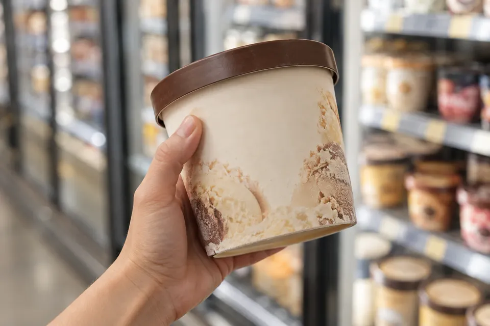 Mano sosteniendo un pote de helado para leer el envase